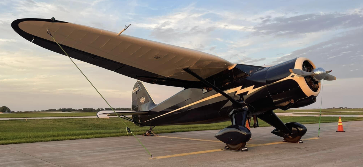 A polished Stinson high-wing taildragger on the ramp at sunset